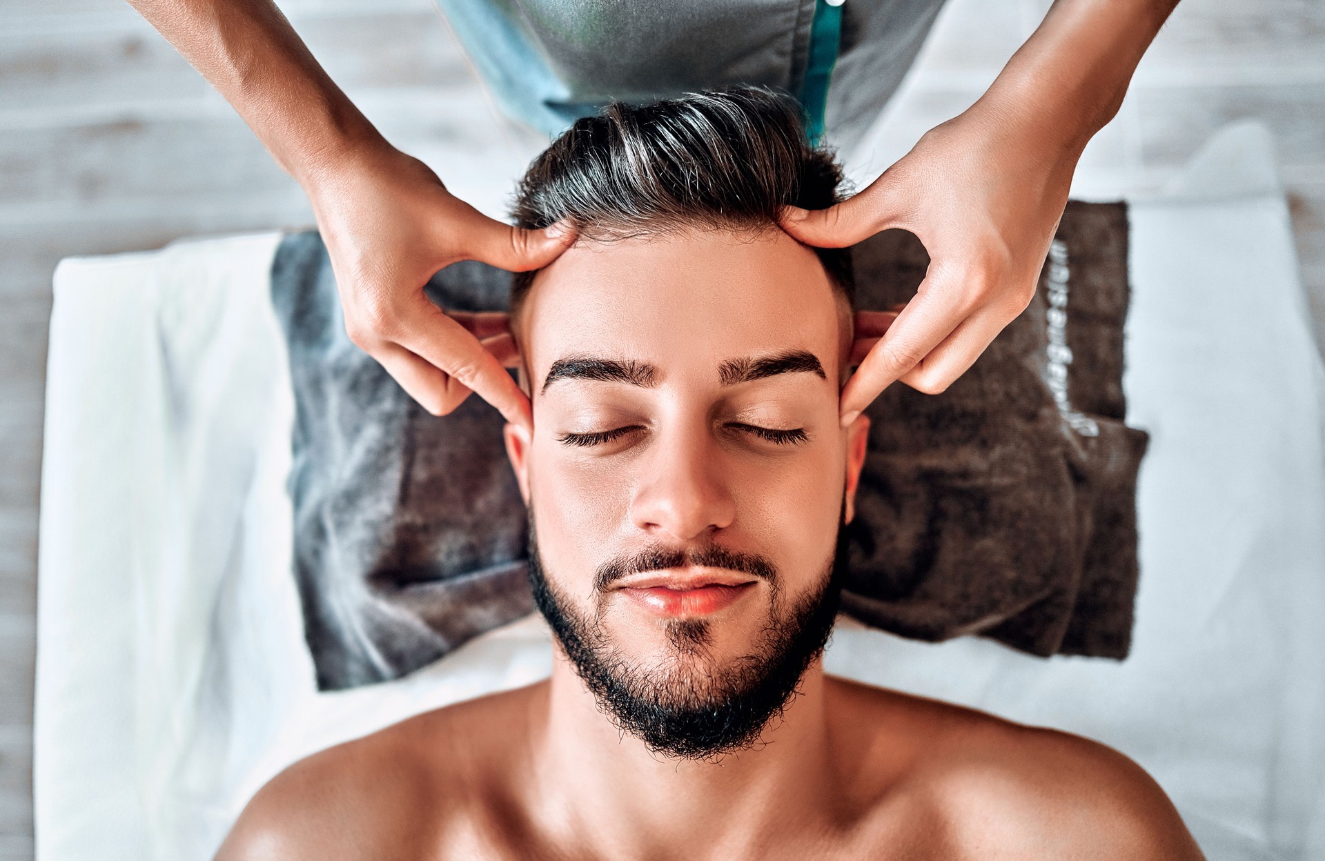Handsome man having scalp massage in spa salon