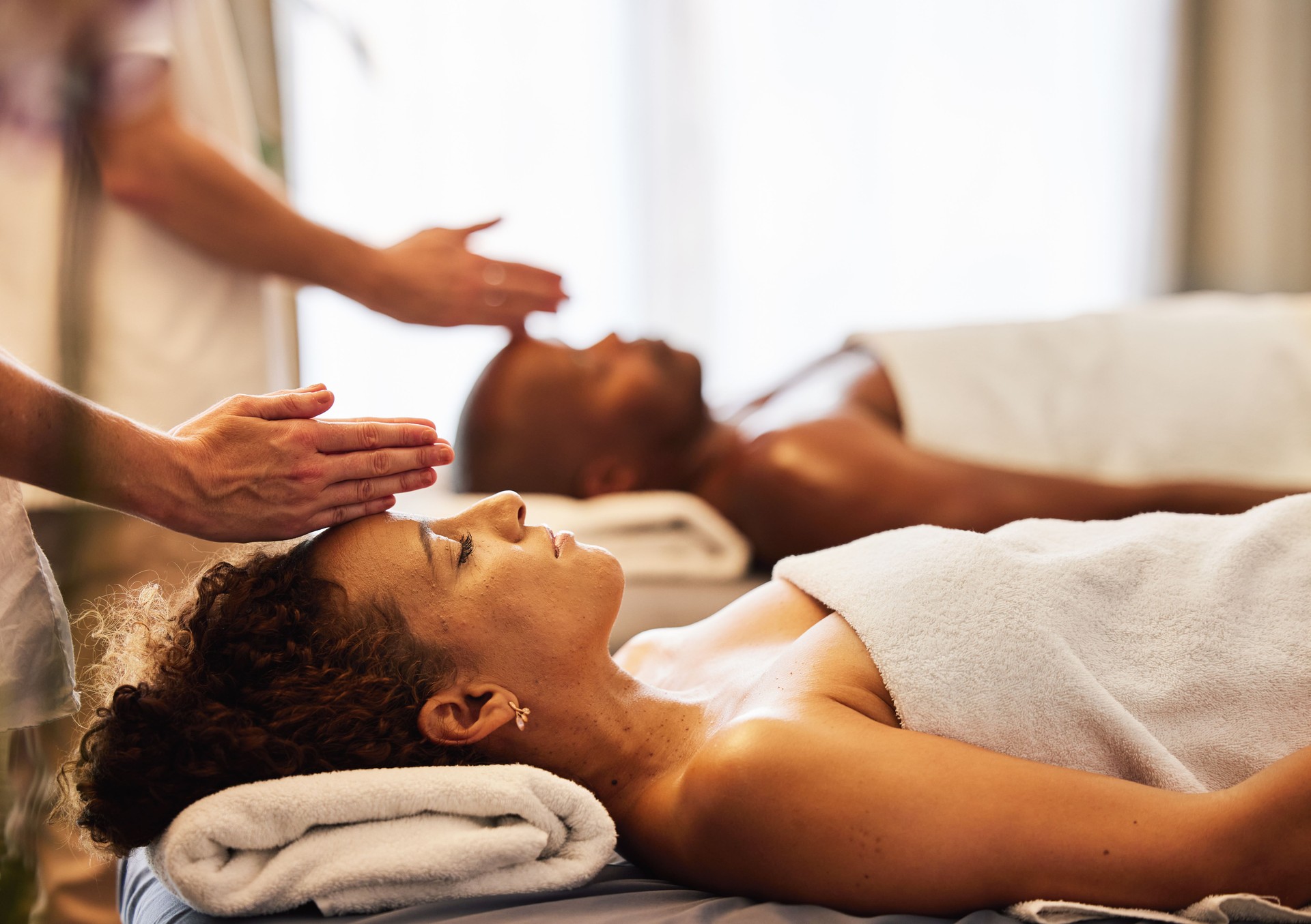 Black couple, head massage and luxury spa to relax in a room for health, wellness and physical therapy. Man and woman on table for skincare, body care and hospitality while on a vacation
